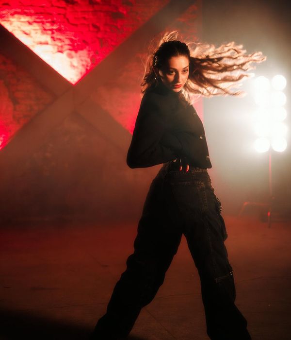 Woman performing energetic movement in dark studio environment